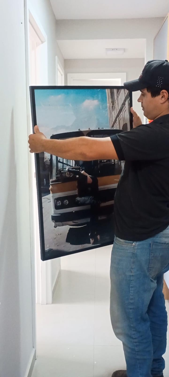 Profissional da JS Faz Tudo fixando um quadro decorativo na parede de uma sala